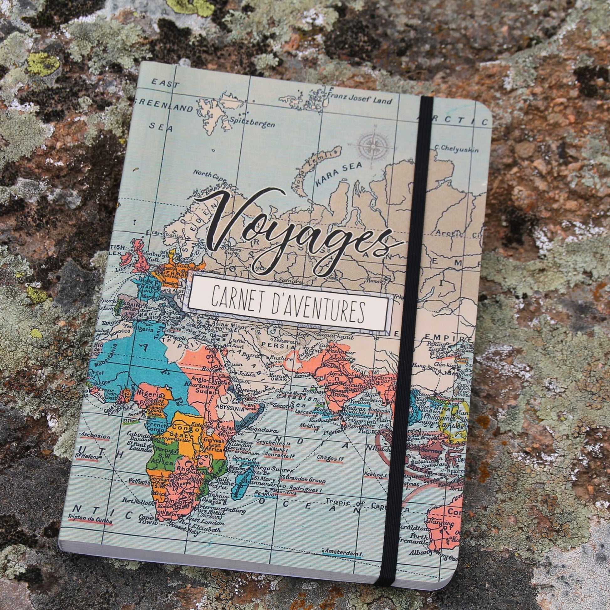 Vue sous un autre angle du carnet de voyage fermé, mettant en valeur les illustrations et l’élastique de fermeture.