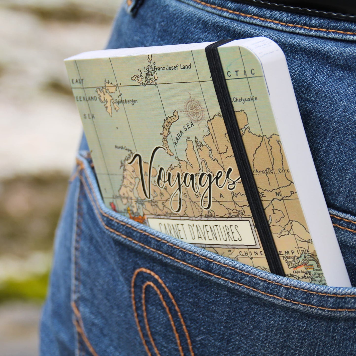 Carnet de voyage format A6 glissé dans la poche arrière d’un jean, illustrant sa praticité pour les voyageurs.