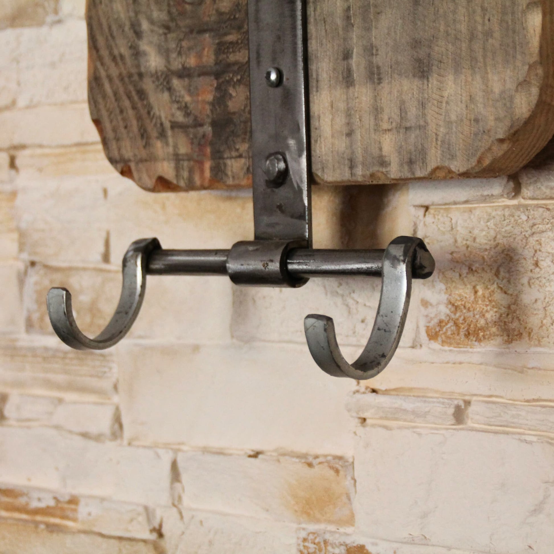 Zoom sur les crochets pour suspendre ses accessoires de moto sur le support de casque moto en bois et métal recyclé.