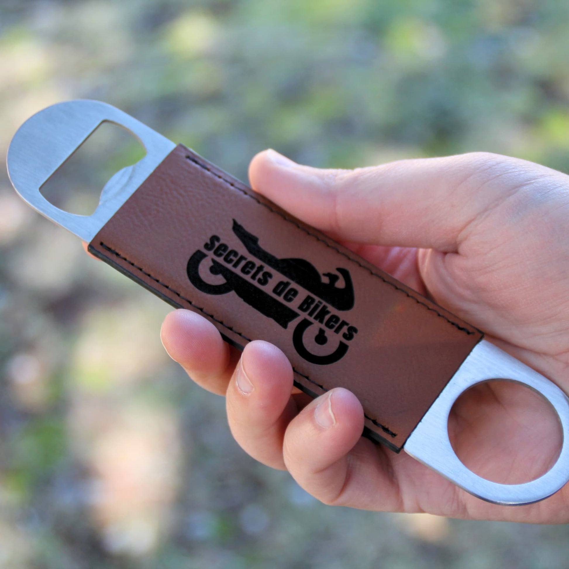 Ouvre-bouteille en cuir marron ergonomique tenu en main, parfait pour une prise en main facile et rapide. Gravé du logo et nom Secrets de Bikers