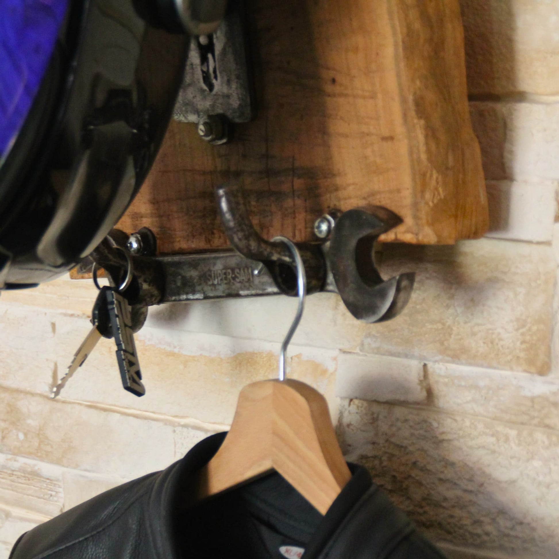 Zoom sur les accessoires suspendus au Support de casque moto en bois fruitier.