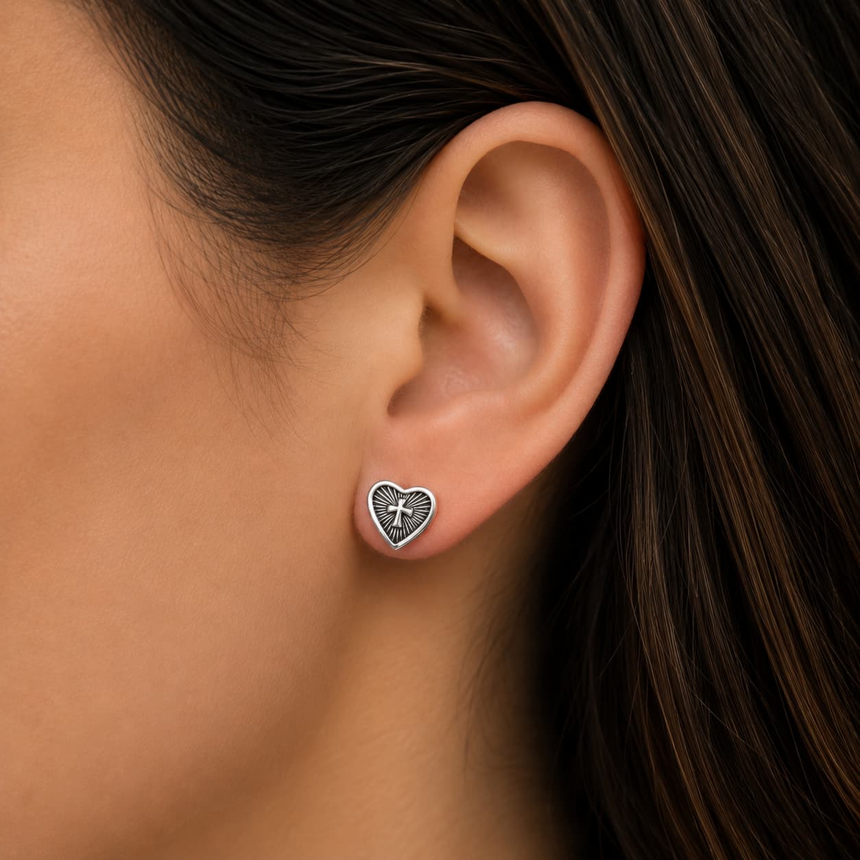 Boucles d'oreilles coeur et croix en acier inox porté par une motarde. Finitions argent
