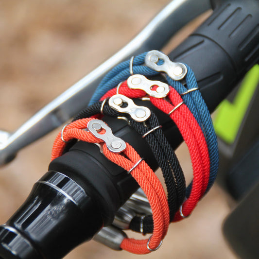 Bracelets cordon colorés aimantés avec maillon de chaine présentés sur un guidon de moto.