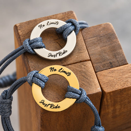 Bracelets motard No Limits Just Ride en finitions argentée et dorée posés sur un support en bois