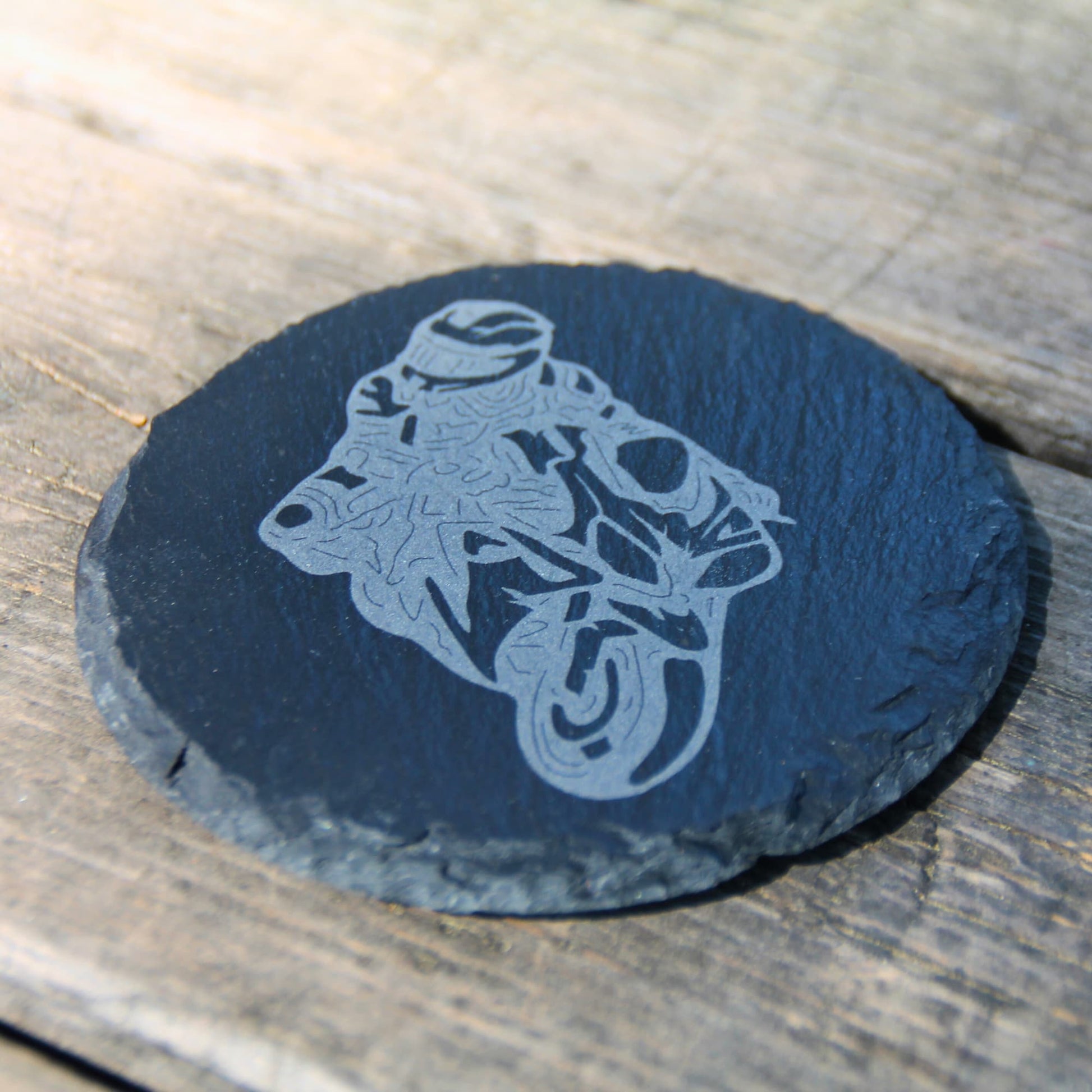 Dessous de verre rond en ardoise naturelle gravé d'un motard. Idée cadeau originale pour les fan de moto !