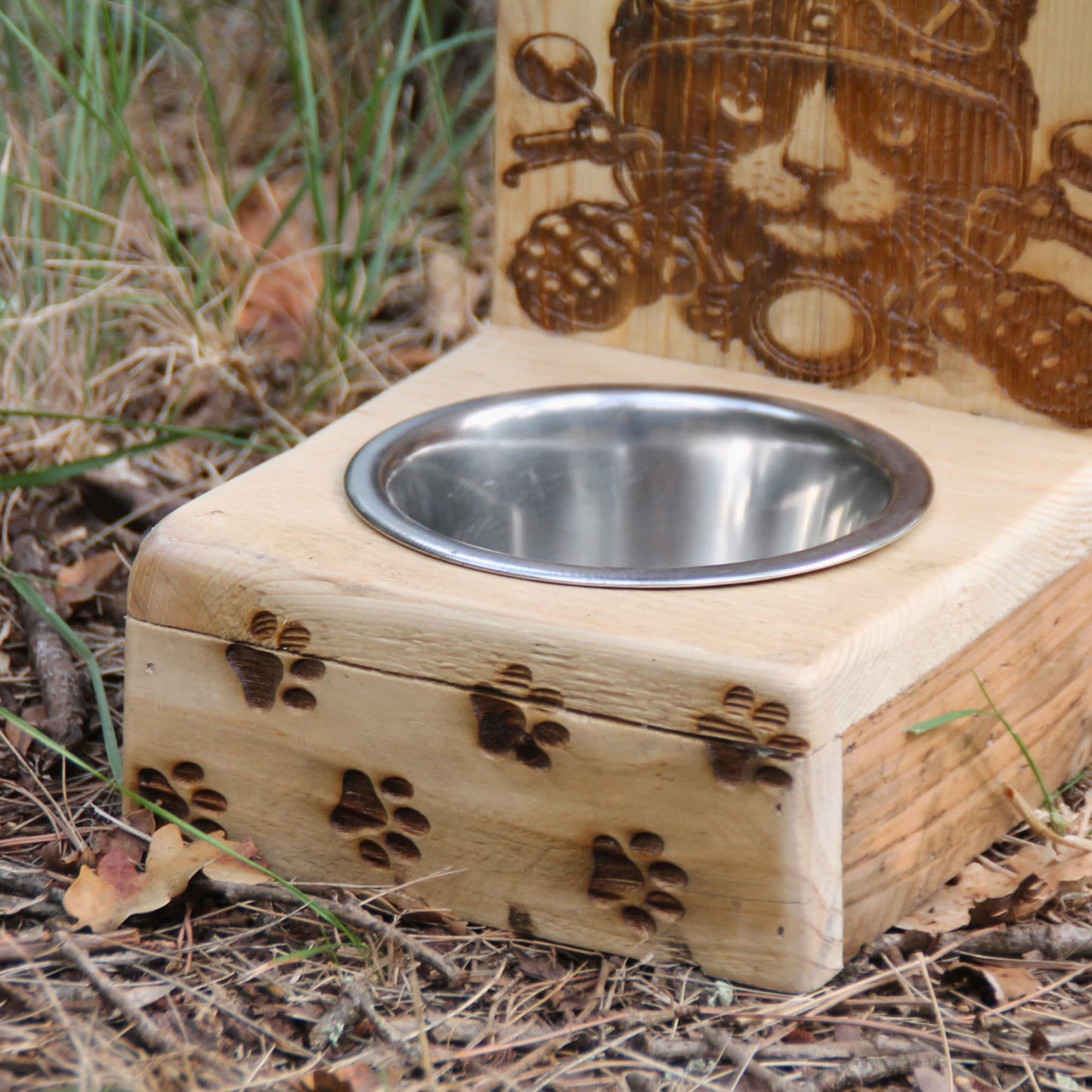 Zoom sur la gamelle pour chat en inox et bois artisanal. Gravure chat motard avec casque au guidon de sa moto et traces de pattes