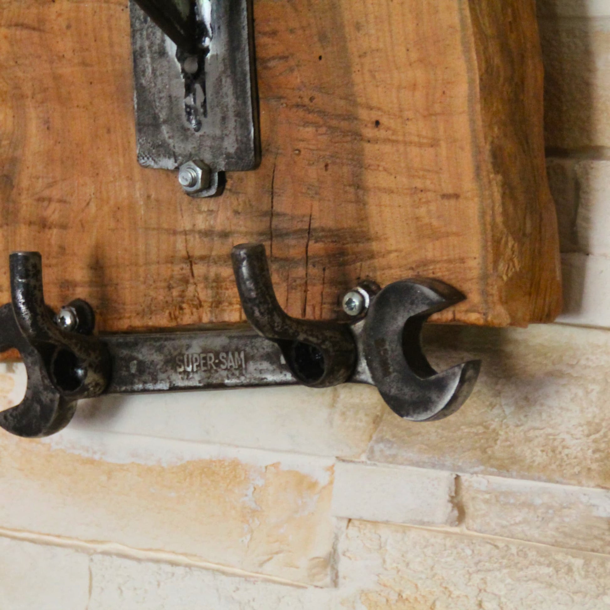 Zoom sur la clé plate tenant les crochets pour accessoires moto du support de casque moto en bois fruitier. Découpe brute, fait main, pièce unique.