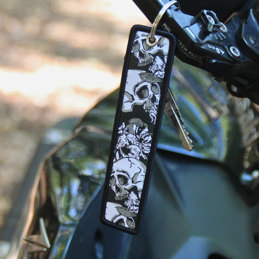 Porte clé moto en tissu noir brodé de cranes et de fleurs. Une idée cadeau pour motard et motarde !