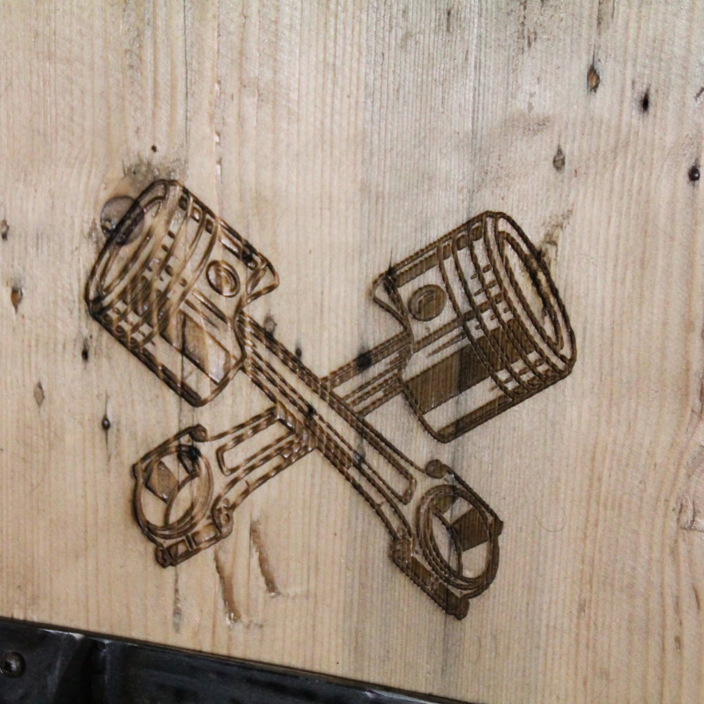 Zoom sur la gravure 'Pistons' du support de casque moto artisanal en bois, ajoutant une touche mécanique unique.