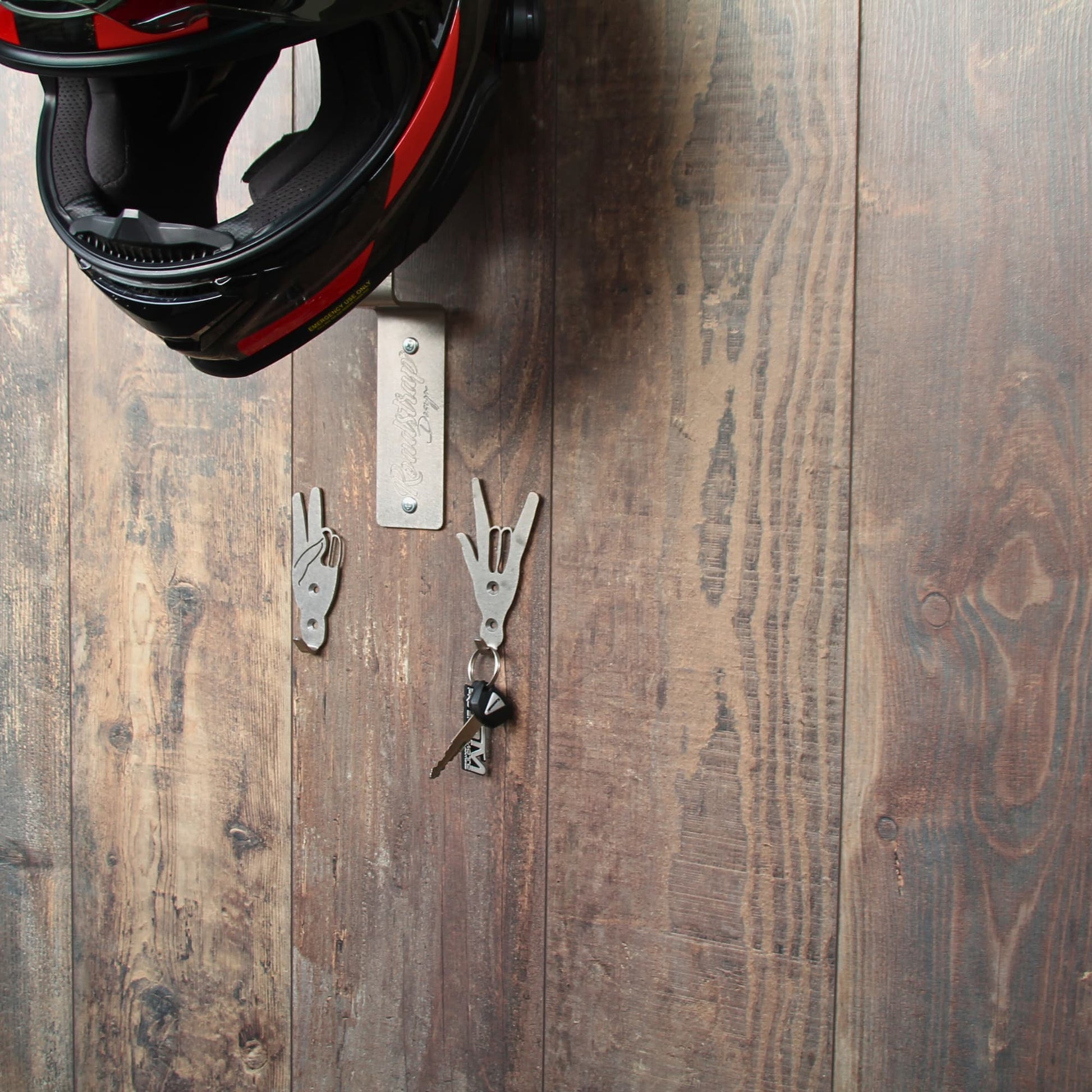 Zoom sur le upport de casque moto en acier en situation avec un casque posé et 2 crochets de rangement.