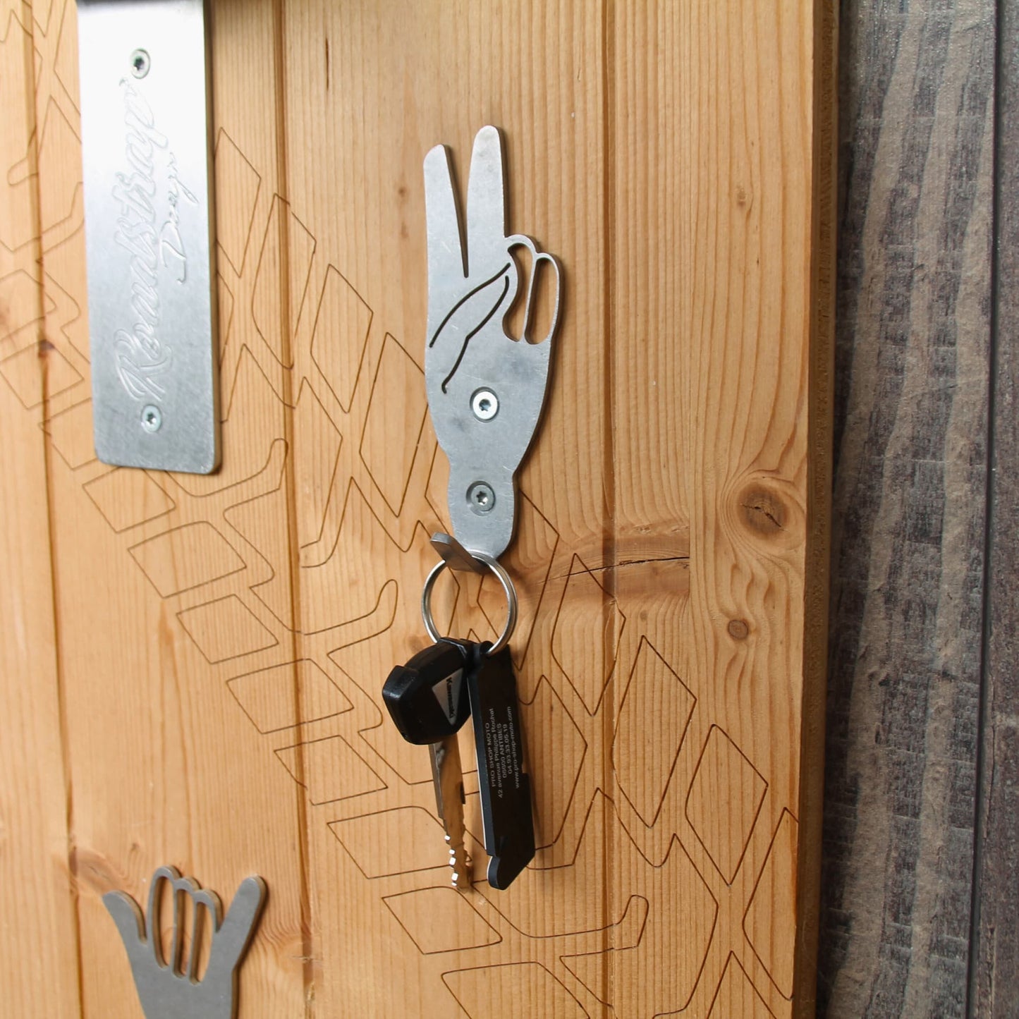 Zoom sur le système de crochets en acier pour suspendre ses accessoires de moto (clé, gants, cache cou, casquette ou veste sur cintre).