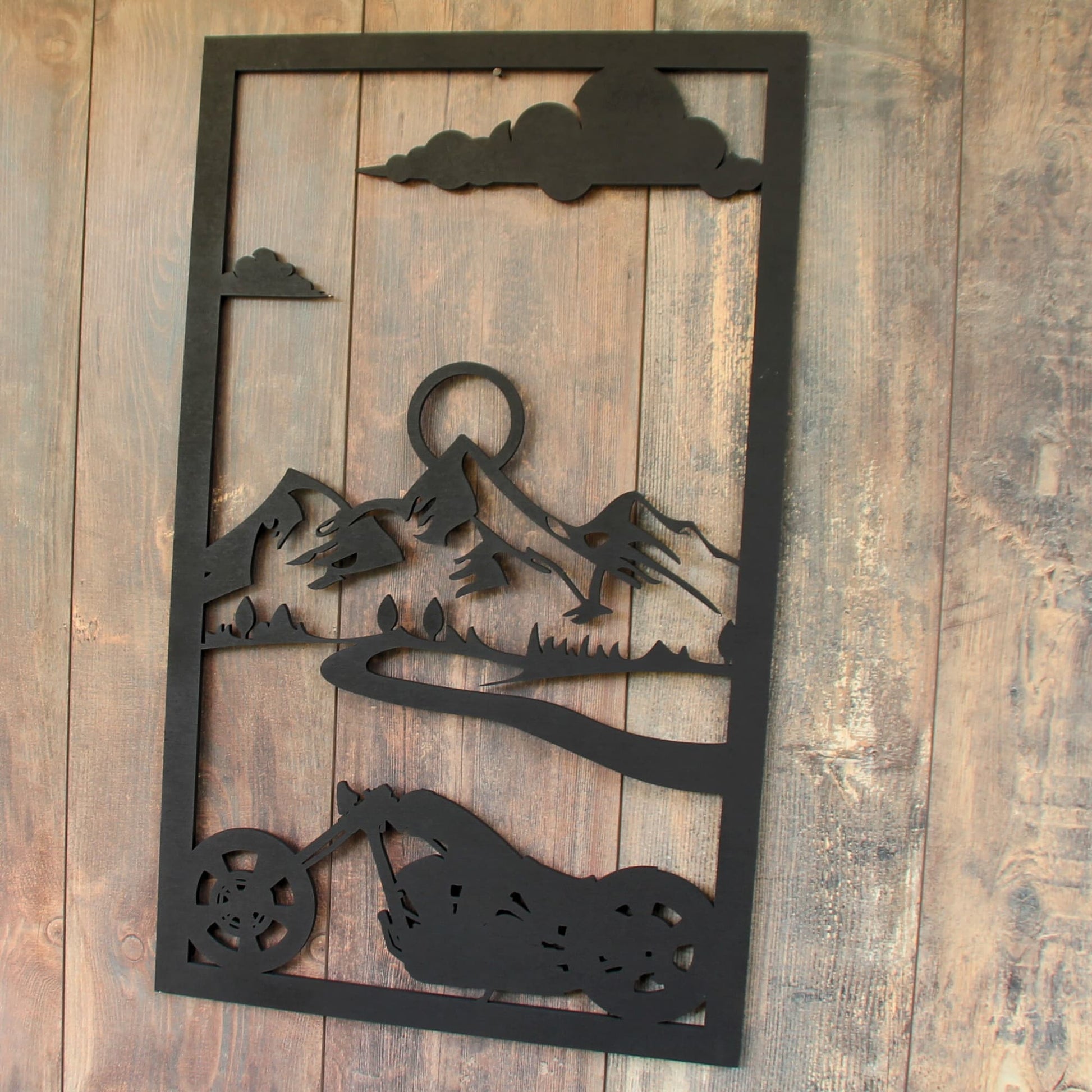 Décoration murale en bois découpé au laser, moto traversant un paysage de montagne.
