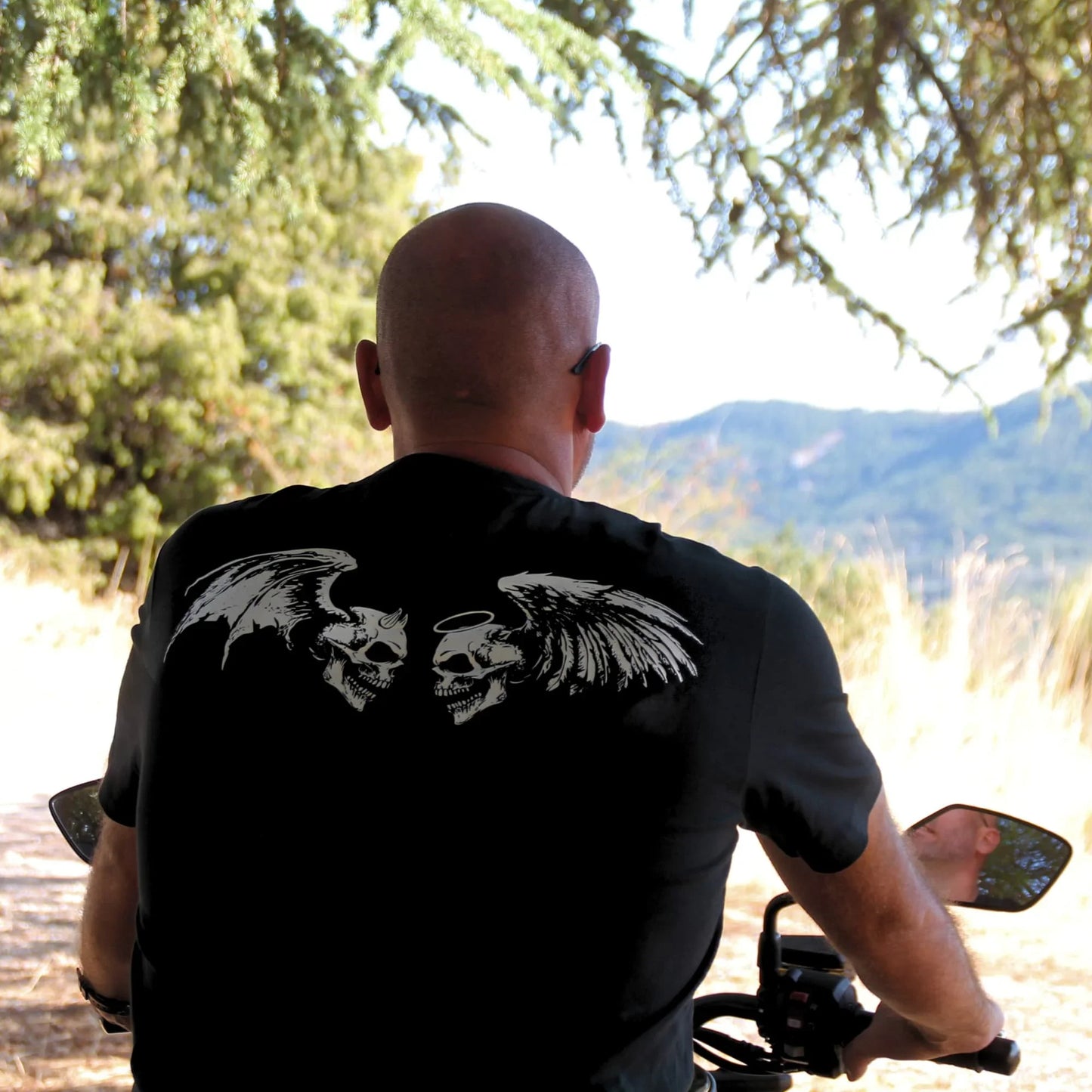 Détails sur le dessin au dos du T-shirt biker en coton. Deux têtes de mort se font face, l'une avec aile et cornes de démon, l'autre avec auréole et ailes d'ange.
