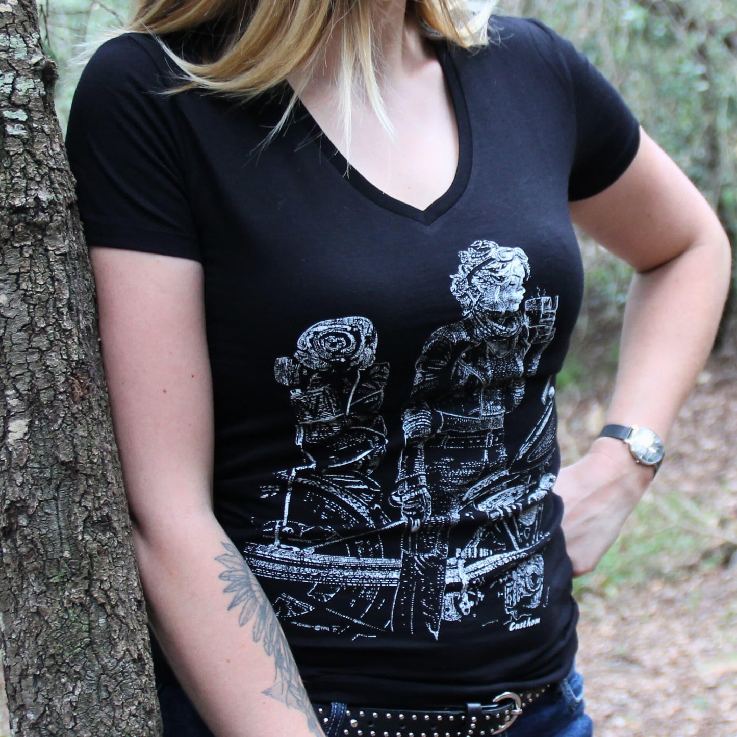 T-shirt col V 100% coton pour femme, porté par une motarde baroudeuse en train de boire un café sur sa moto chargée de bagages.