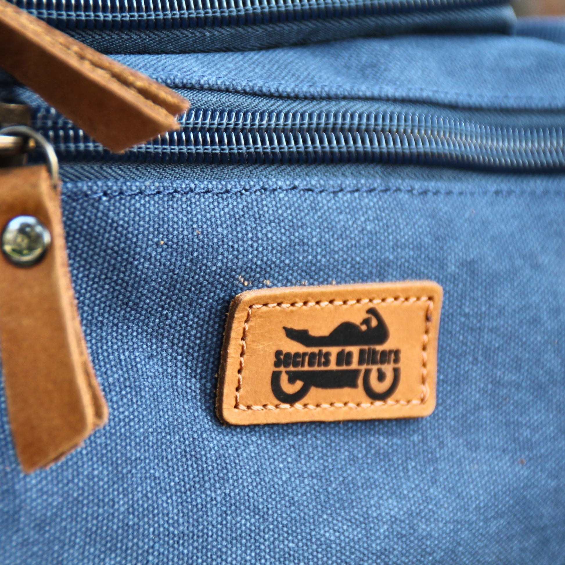 Zoom sur les détails en cuir sur la trousse de voyage en tissu.