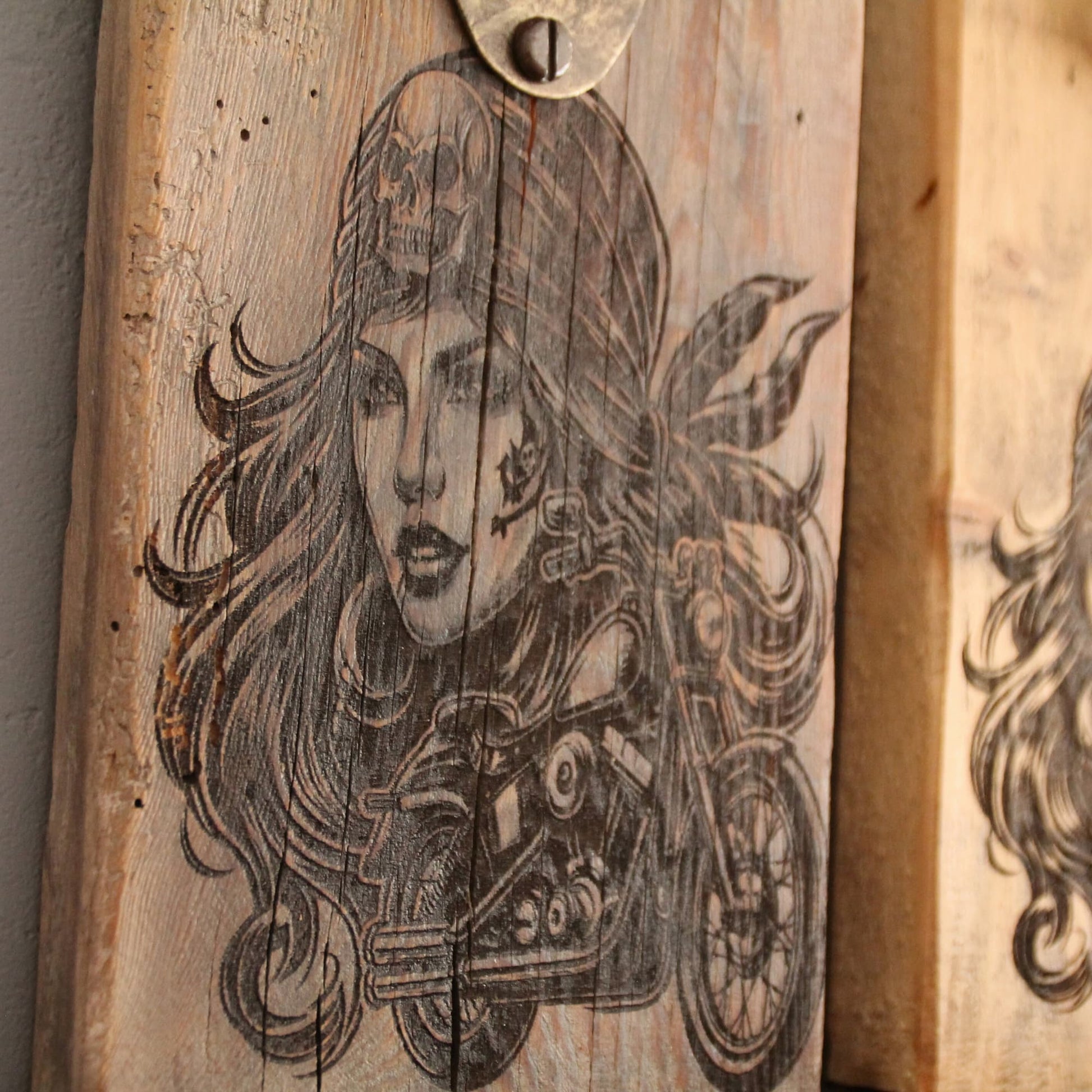 Zoom sur la gravure du décapsuleur mural en bois sombre et métal recyclé. Fait main. Gravure pirate motarde sexy.