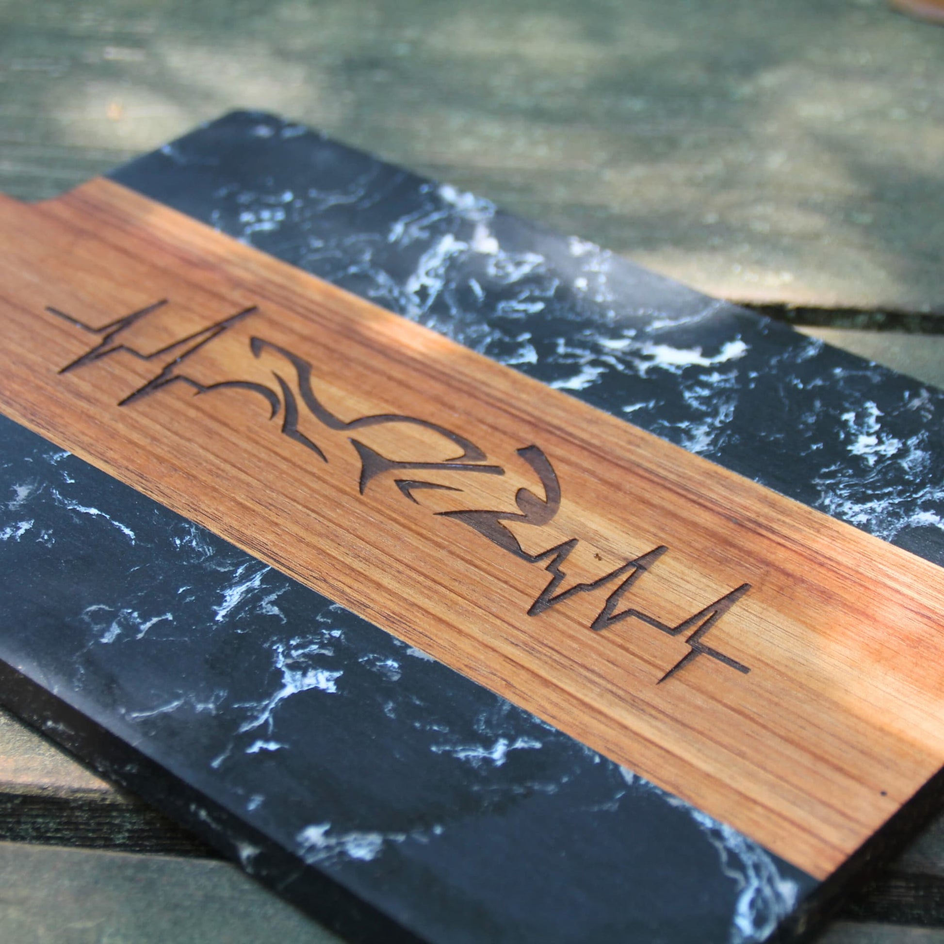 Planche à découper en bois et marbre gravée d'une ligne de vie traversant une moto.