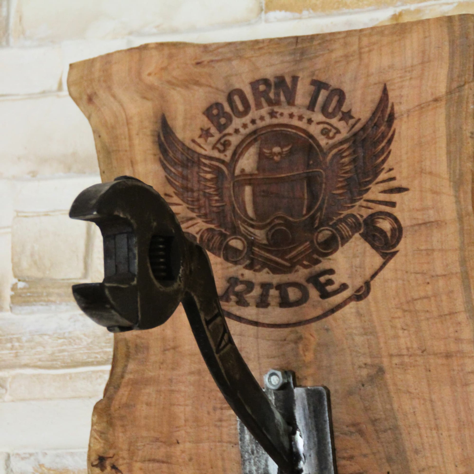 Zoom sur la gravure et la clé à molette courbée ancienne du support de casque moto en bois fruitier. Découpe brute, fait main, pièce unique.