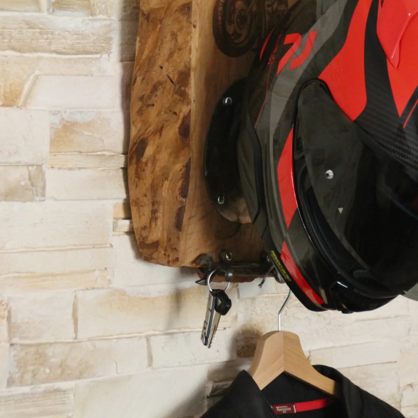 Accessoires et casque posés sur le support de casque moto fait main en bois fruitier et métal recyclé. Gravure moto custom.