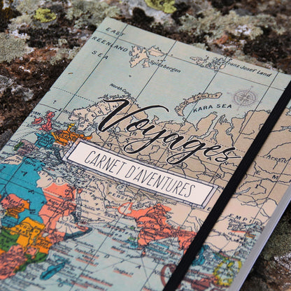Gros plan sur la couverture du carnet de voyage, montrant les détails des illustrations de destinations et de la mappemonde.
