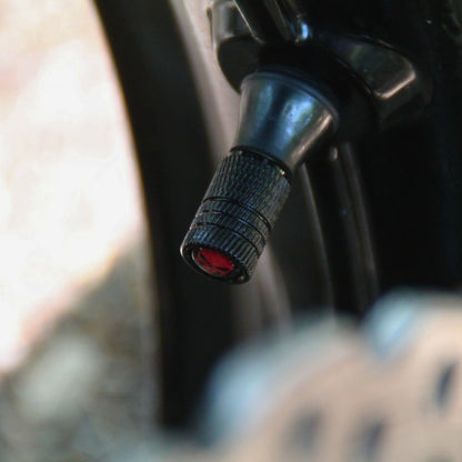 Vue de profile en situation des bouchons de valve moto noirs et crâne rouge punisher.