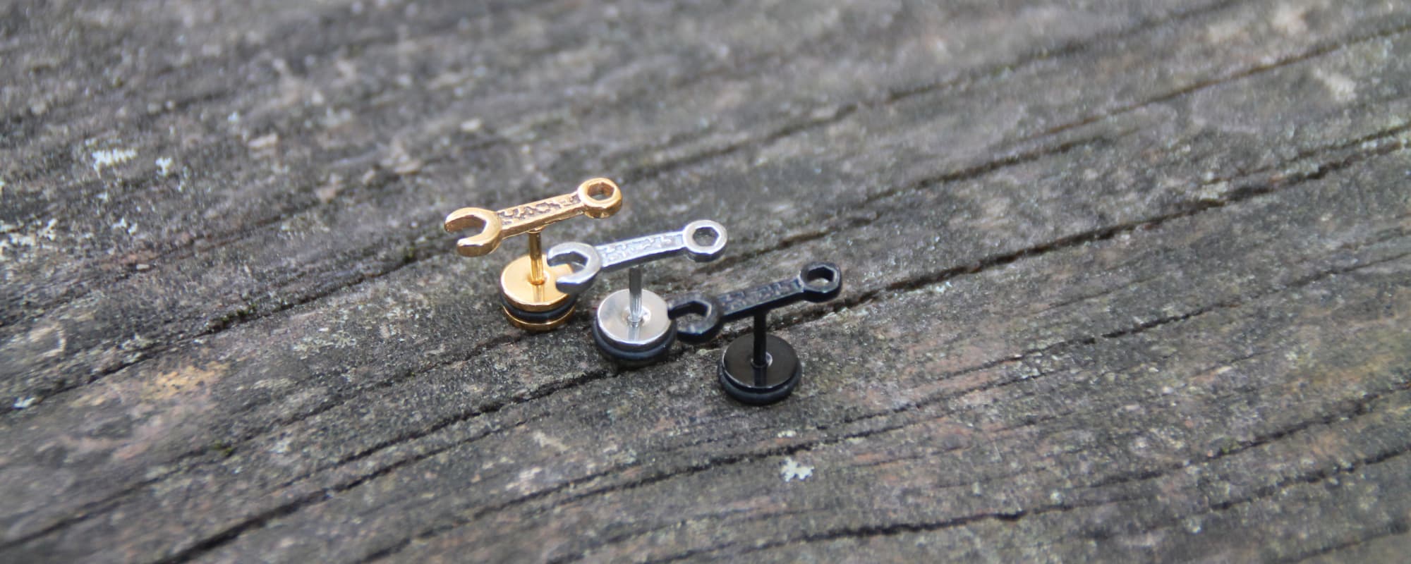 Boucles d'oreilles en acier inoxydable en forme de clé mécanique. Embout plat et vissé, spécial casque de moto pour ne pas les perdre ni avoir mal.