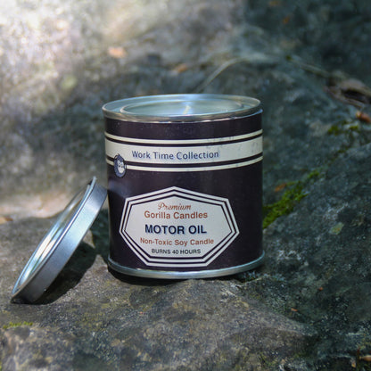 Vue en plongée d’une bougie à la cire de soja, 230g, avec étiquette industrielle "huile moteur", ambiance masculine et brute.