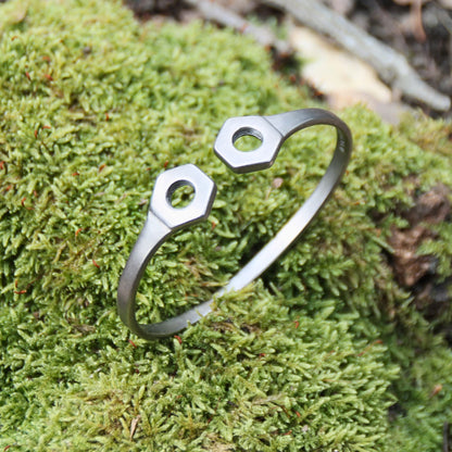 Bracelet jonc en acier inoxydable argenté, design en forme d’écrous, de la marque Rouille, fabriqué en Italie.