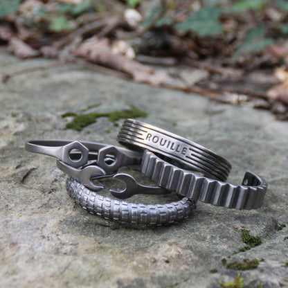 Photo d'ambiance de 5 bracelets joncs en acier inoxydable argenté de la marque Rouille – Designs inspirés par des écrous, engrenages et moteurs.