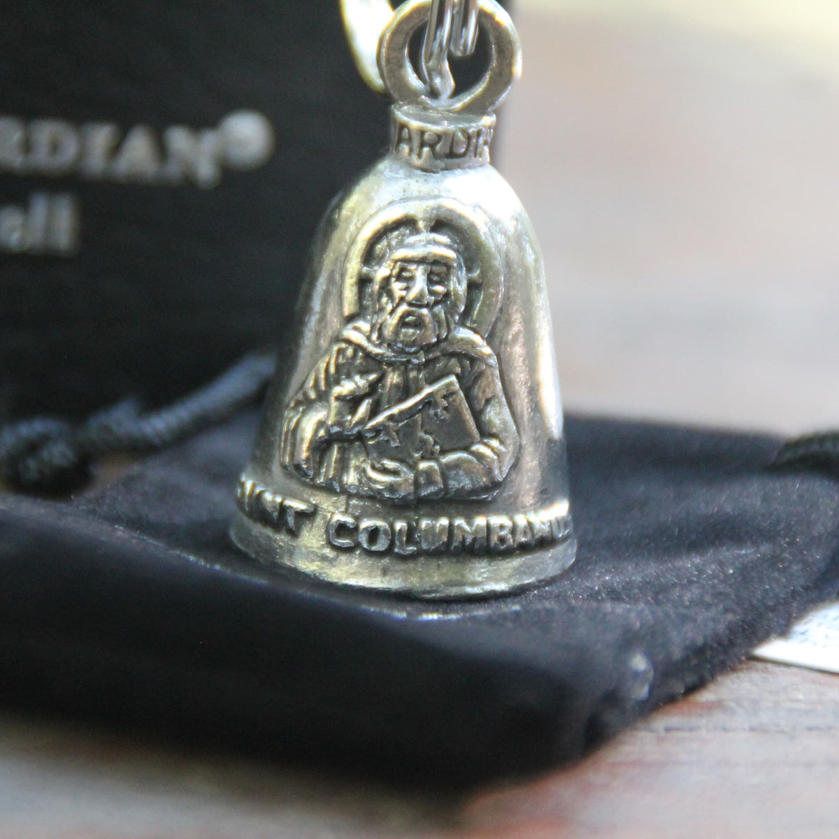 Détail de la clochette Guardian Bell Saint Colomban posé sur sa pochette velours noire