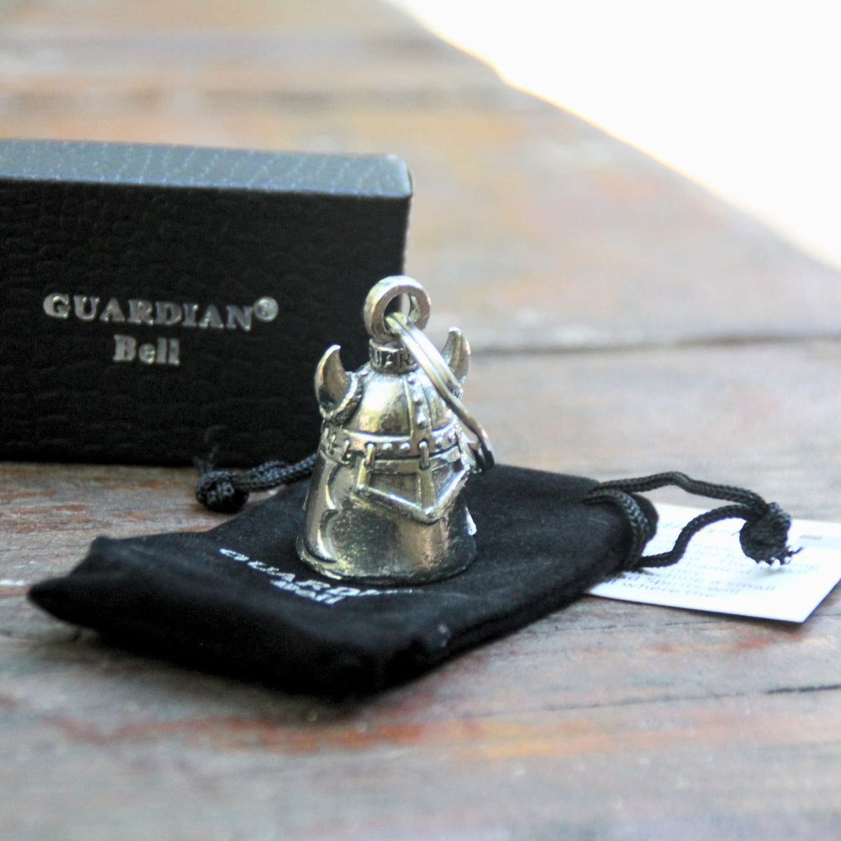 Clochette moto Guardian Bell Casque Viking avec casque à cornes posé sur sa pochette velours noire