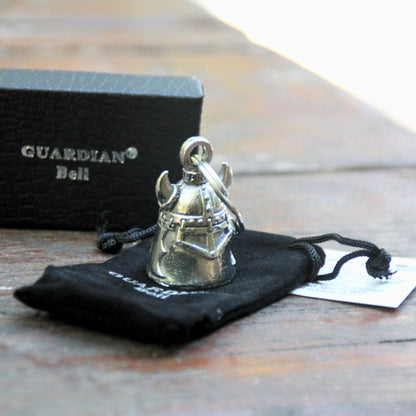 Clochette moto Guardian Bell Casque Viking avec casque à cornes posé sur sa pochette velours noire