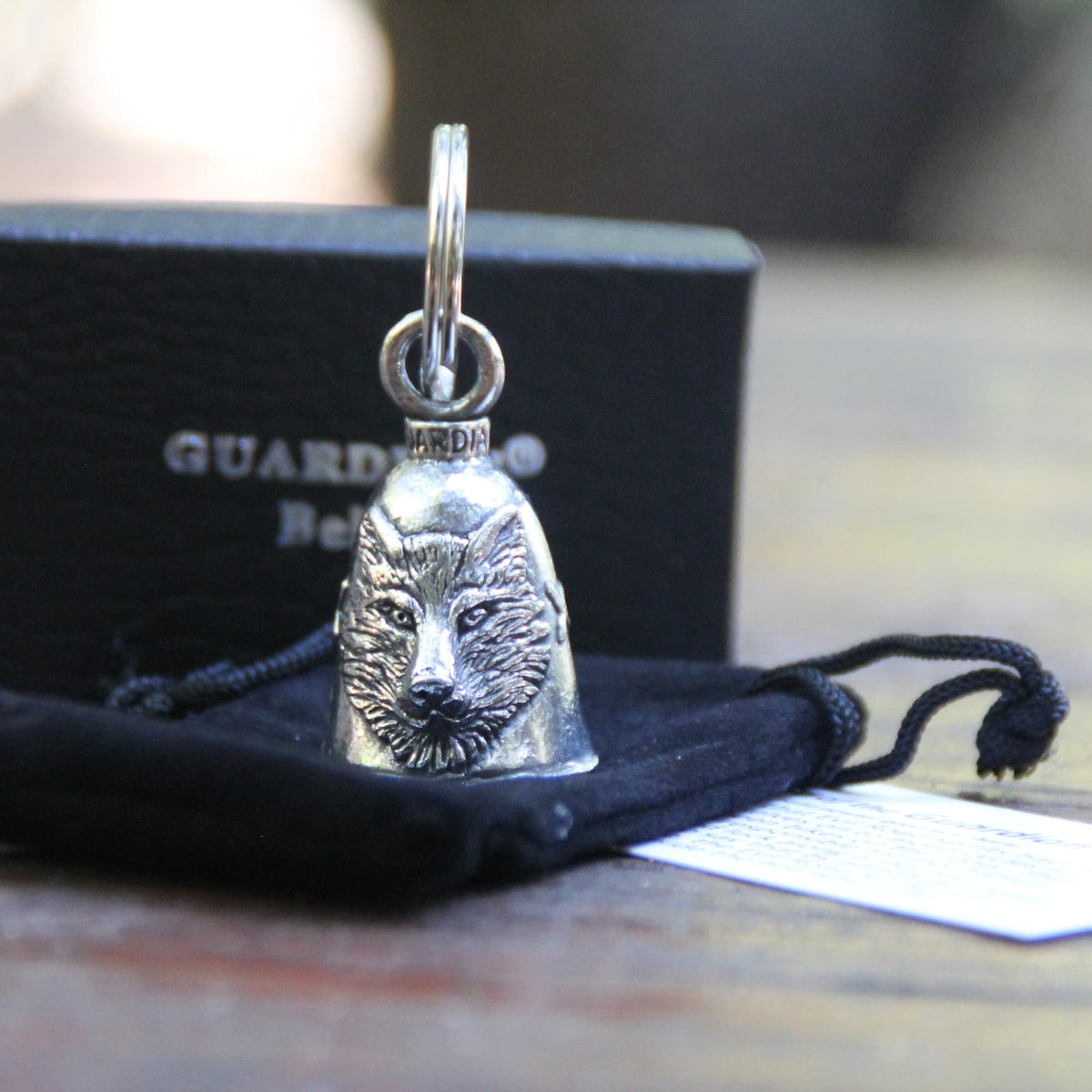 Clochette moto Guardian Bell loup officielle posée sur sa pochette en velours noire.