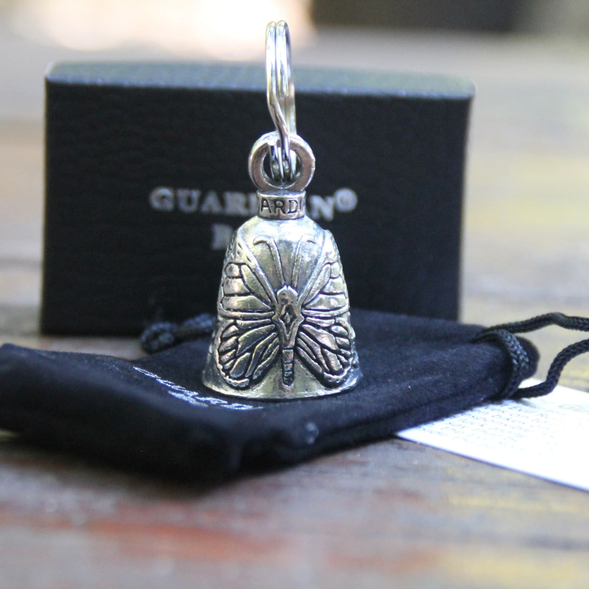 Clochette moto Guardian Bell papillon sur sa pochette en velours noire