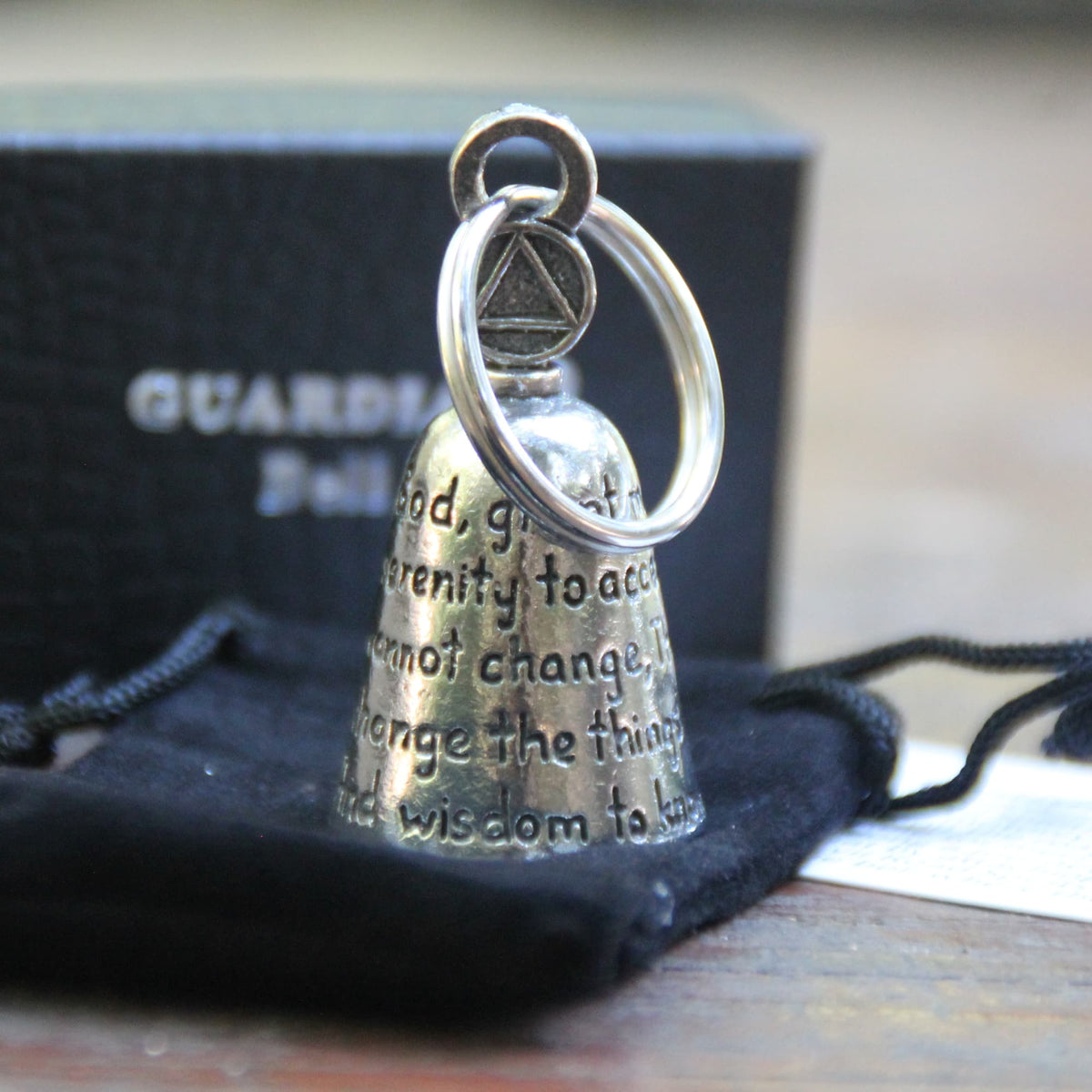 Guardian Bell Prière de la sérénité posée sur sa pochette en velours noir et sa carte de la légende