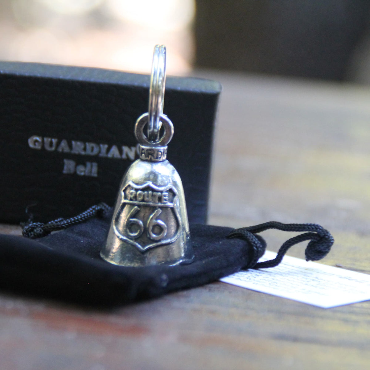 Clochette moto Guardian Bell Route 66 posée sur sa pochette en velours noirs, prête à offrir à un motard !