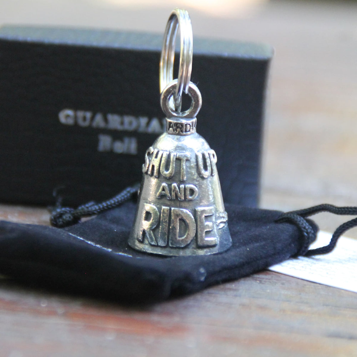 Guardian Bell Shut Up and Ride avec sa pochette officielle en velours noir et sa carte de la légende