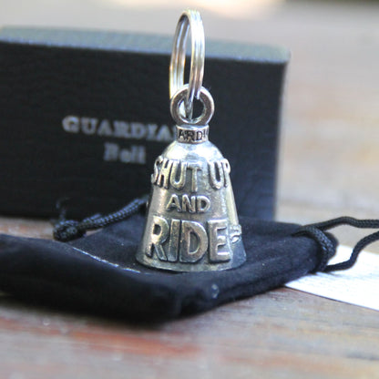 Guardian Bell Shut Up and Ride avec sa pochette officielle en velours noir et sa carte de la légende