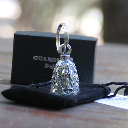 Clochette moto Guardian Bell officielle Vierge Marie posée sur sa pochette velours devant la boite cadeau