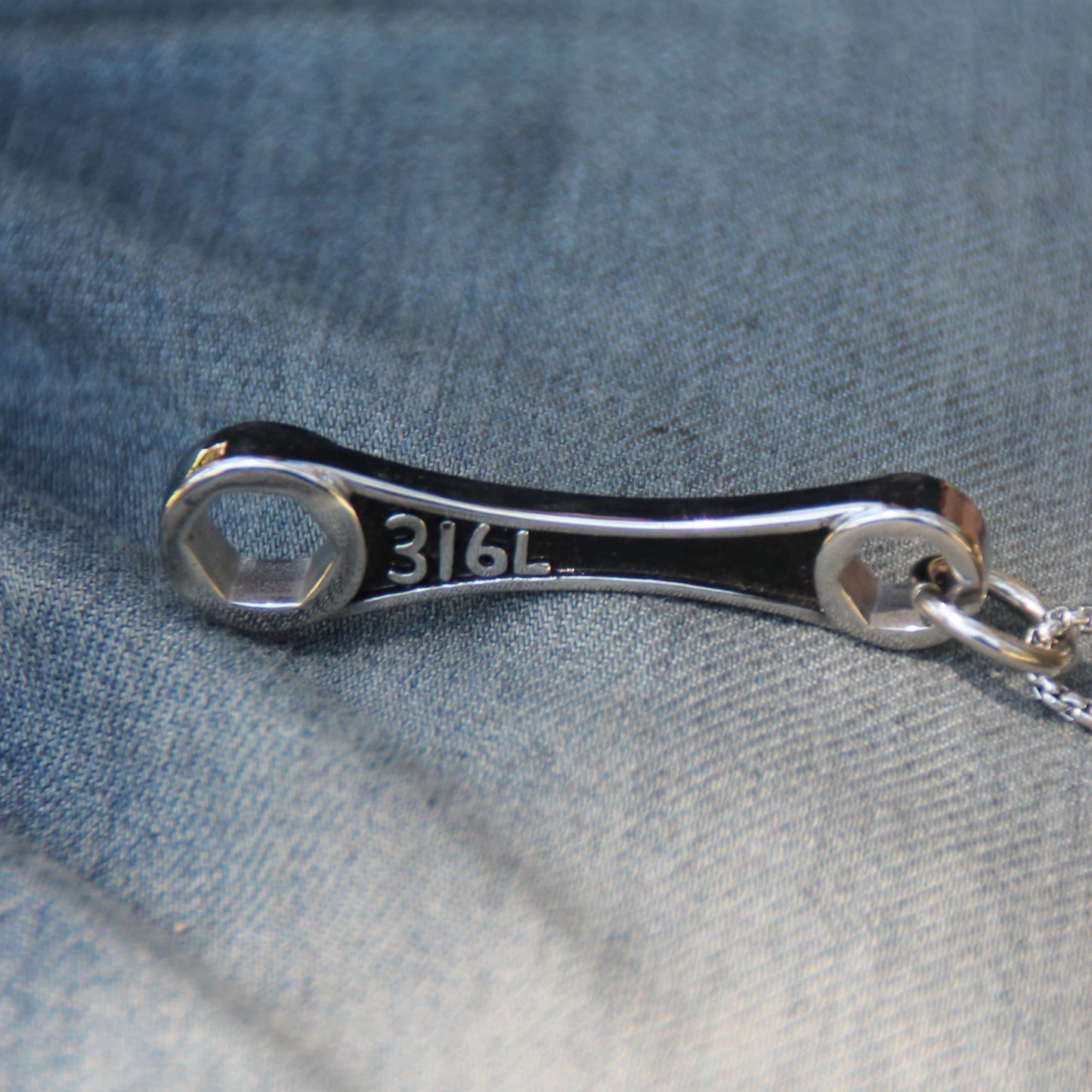 Zoom sur le pendentif argenté clé mécanique du collier acier inox. 