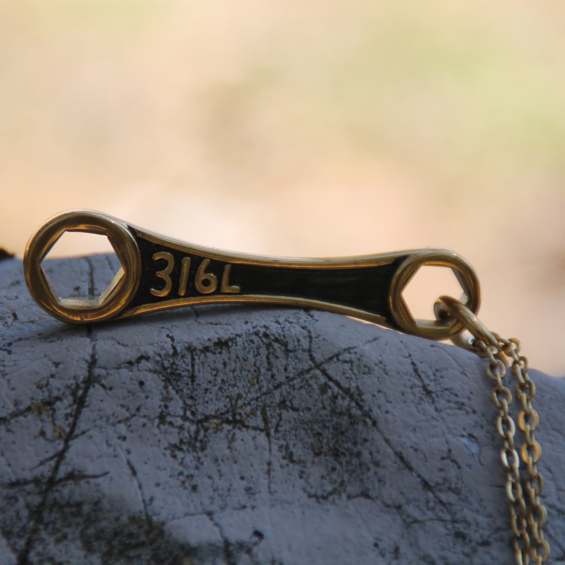 Zoom sur le collier pendentif clé mécanique acier inoxydable doré. 