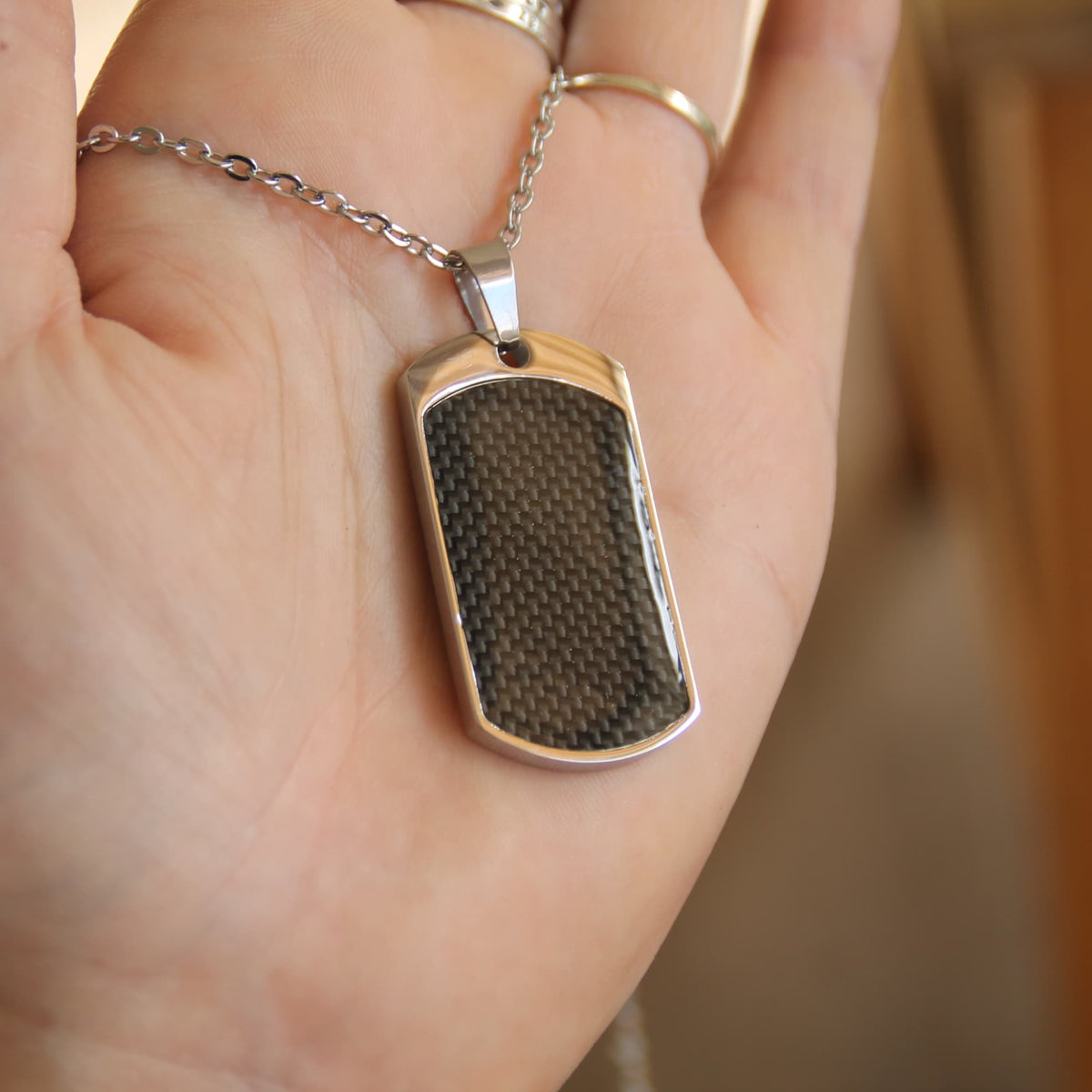Zoom sur le collier motard en acier inoxydable et pendentif en fibre de carbone