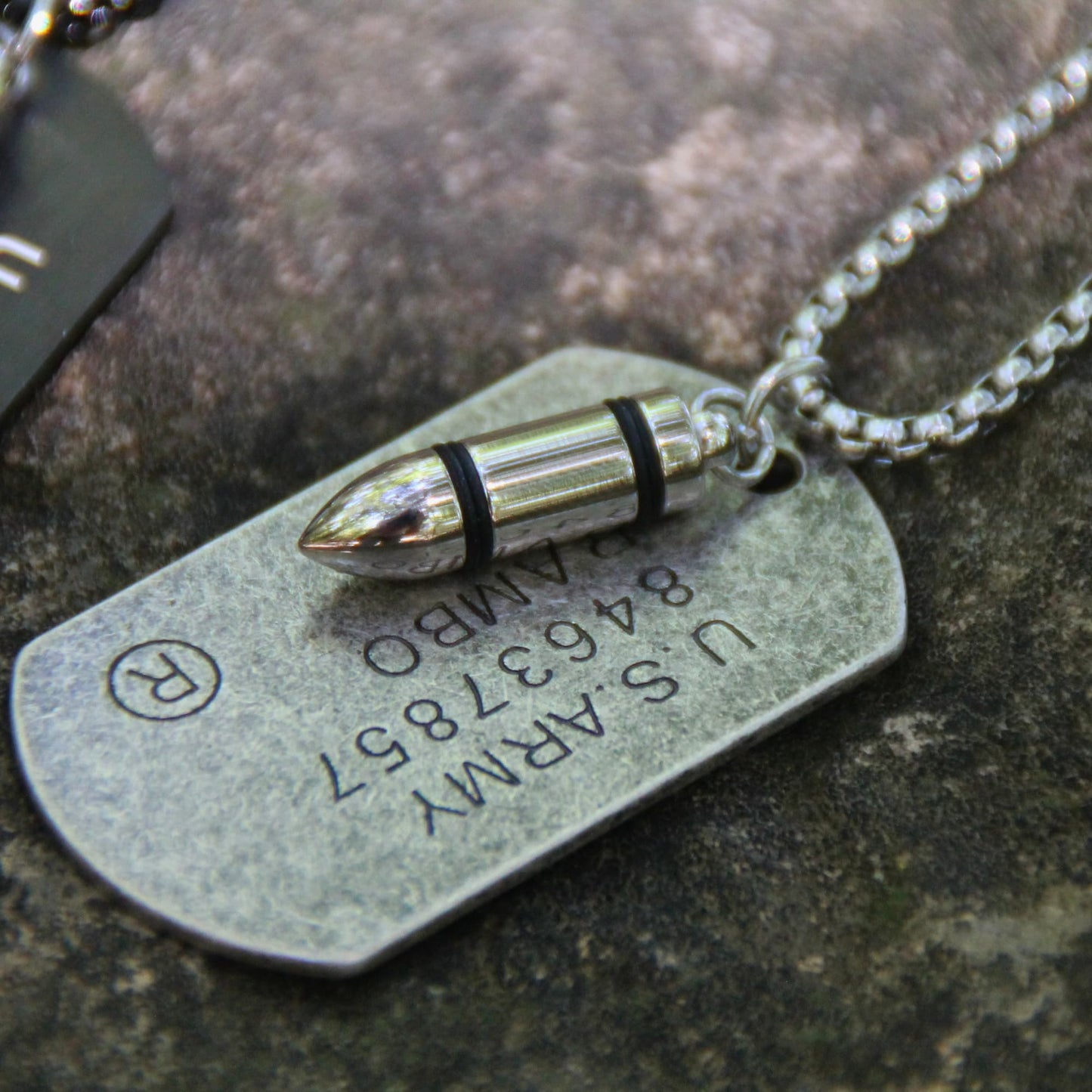 Détail de la plaque militaire du collier Rambo et sa balle.
