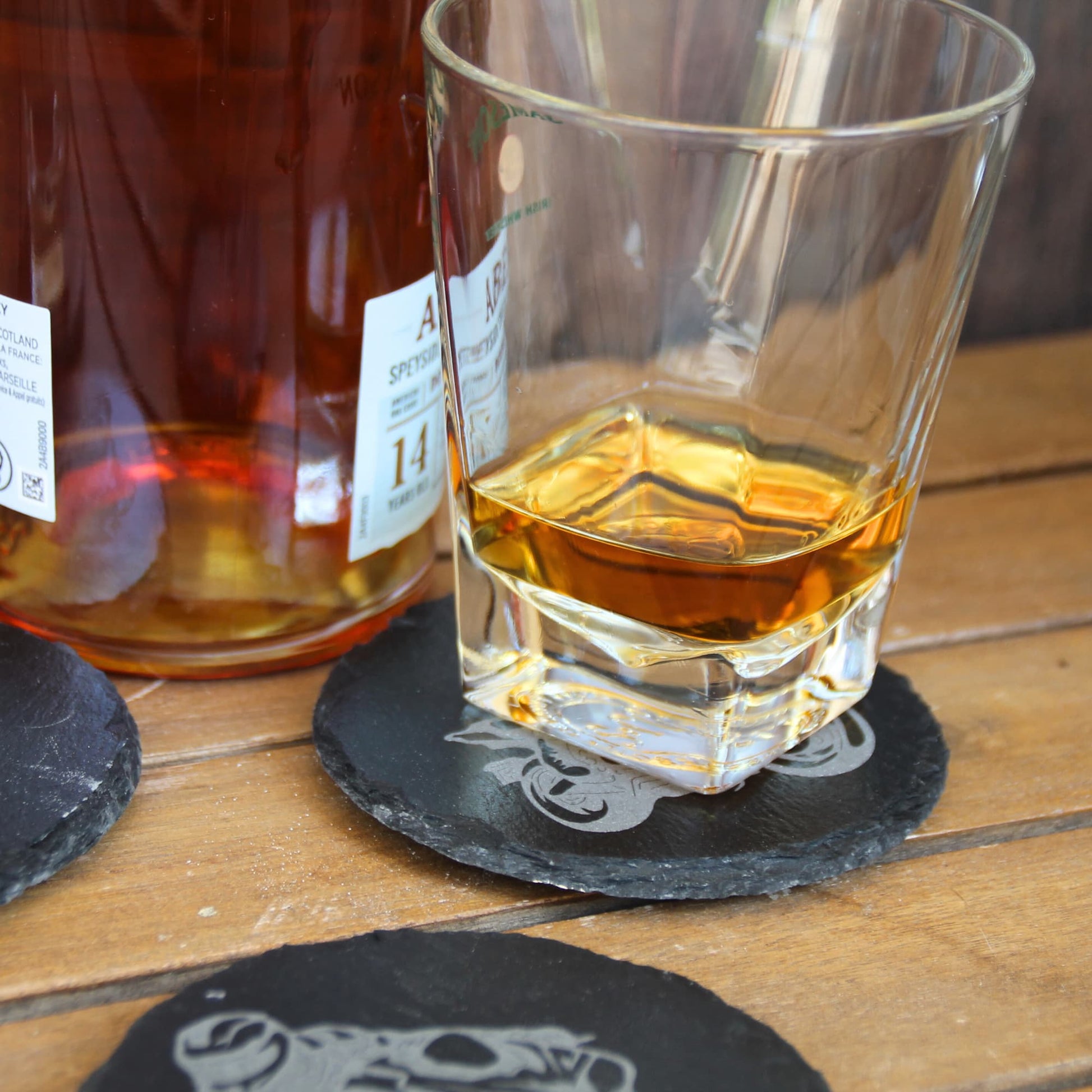 Dessous de verre en ardoise présenté avec un verre rempli.