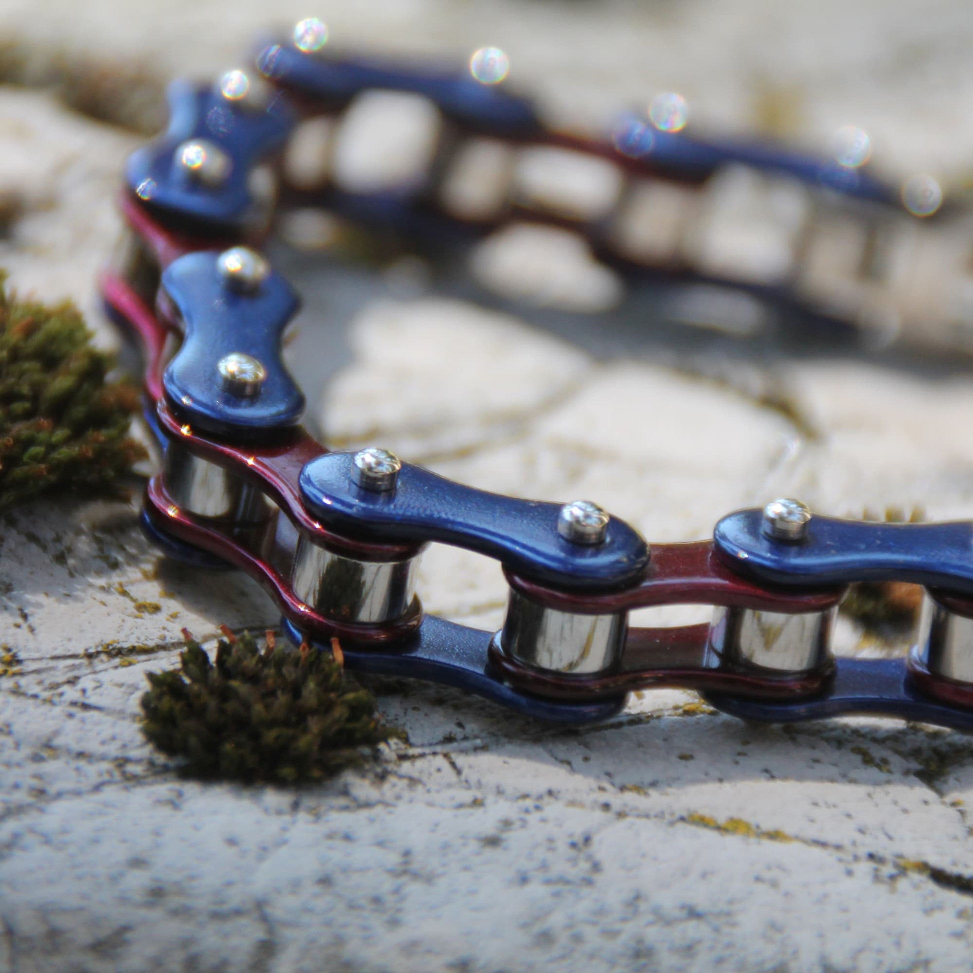 Zoom sur le bracelet style chaine de moto en acier inoxydable couleur bleu et pourpre.
