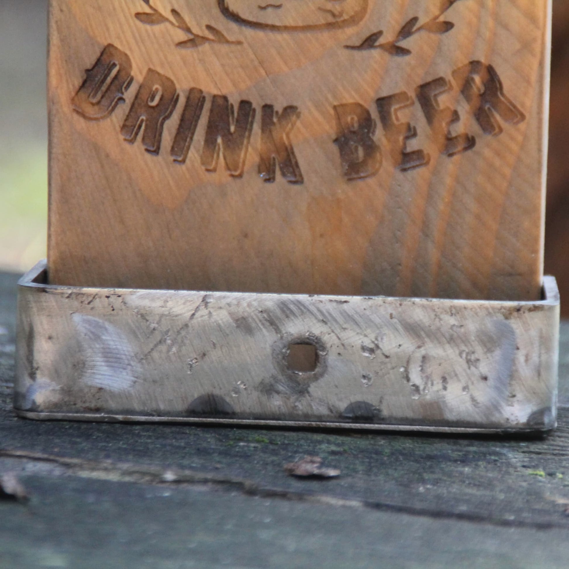 Détails du bac de récupération des capsules du décapsuleur mural en bois gravé.