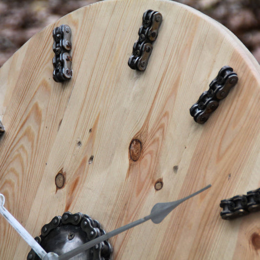 Zoom sur les chaines de moto représentant les heures sur l'horloge en bois