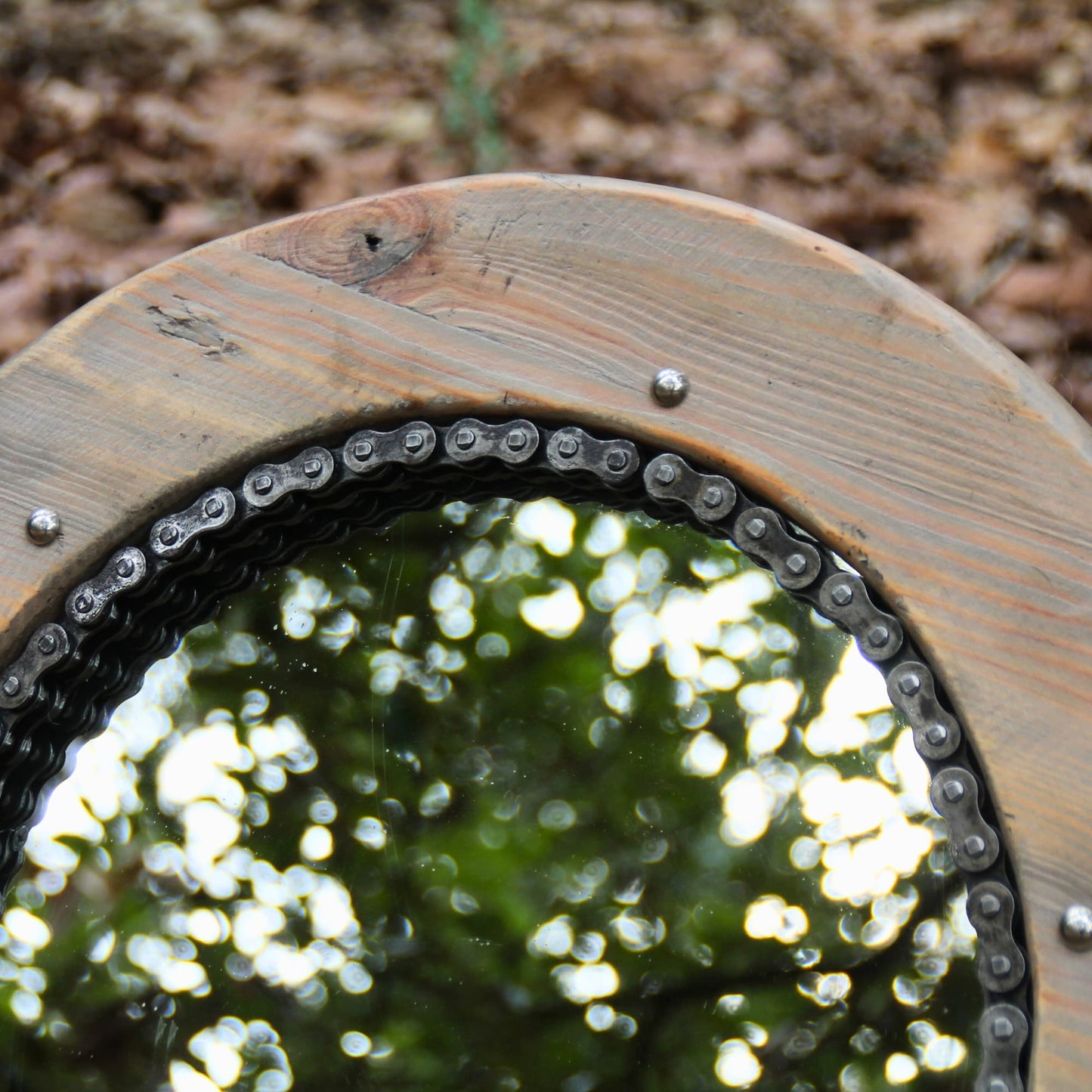Details du bois brut, de la chaine de moto et des pieces mécaniques utilisées pour le miroir artisanal rond. 