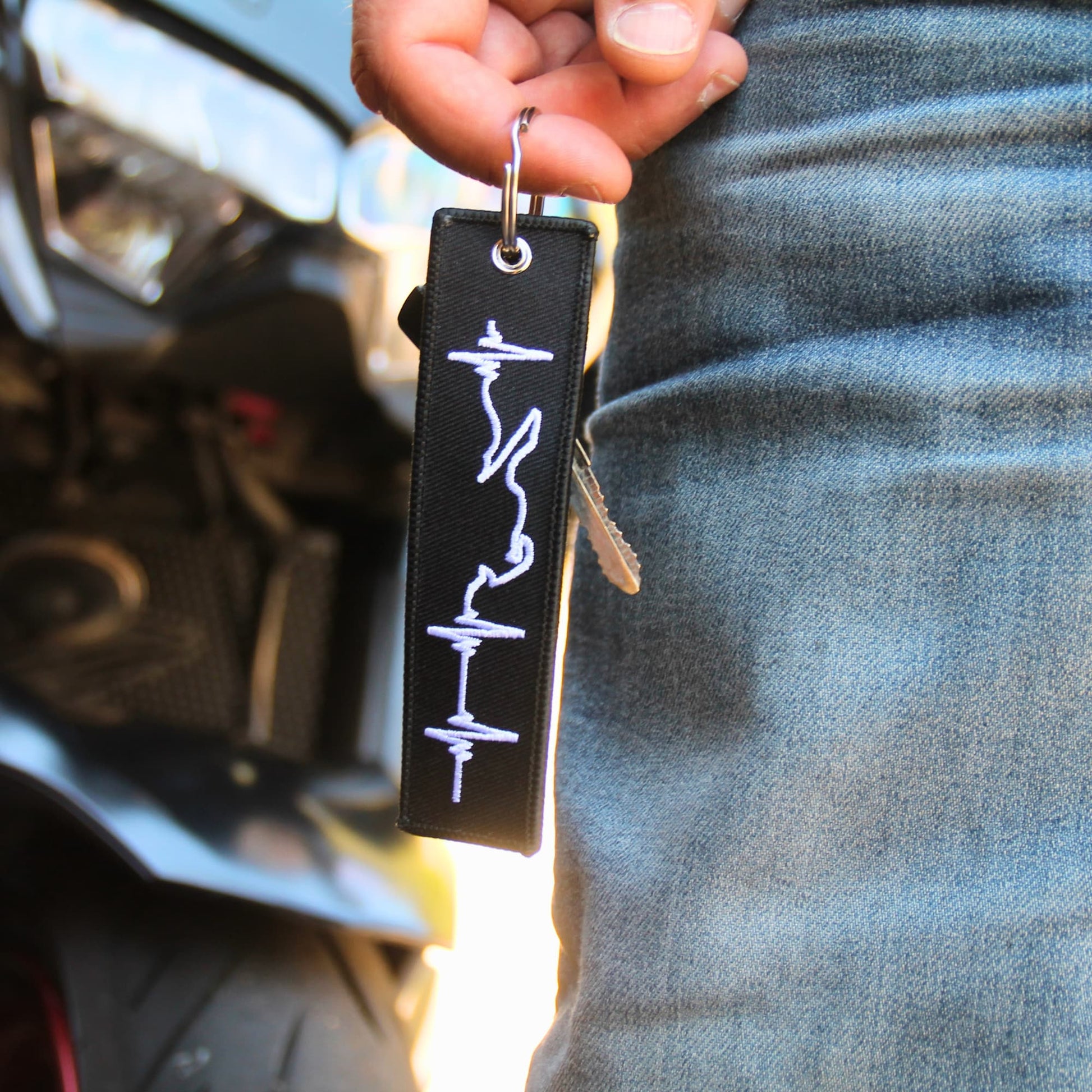 Idée cadeau motard porte clé blanc brodé ligne de vie tenu en main