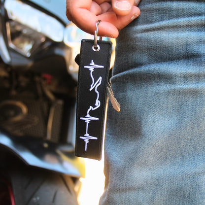 Idée cadeau motard porte clé blanc brodé ligne de vie tenu en main